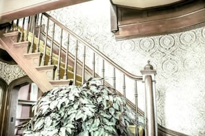 Stunning staircase with ornate railings and a large, lush plant.