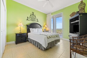 A bedroom with a bed, two bedside tables with lamps, a dresser, a TV, and a balcony with a view.