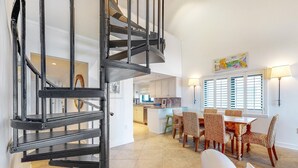 Una cuina àmplia amb zona de menjador, una escala espiraltra i vista a la zona de sala d'estar.