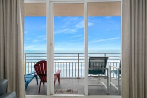 Enjoy the ocean view from this balcony with a set of chairs and a table.