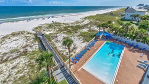 An aerial view of a beachside resort with a swimming pool, beach umbrellas, and a boardwalk leading to the beach. - Seaspray West 603- Gulf Front (Pensacola)