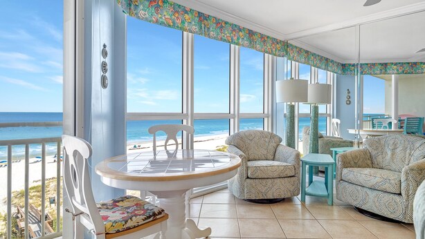 A spacious balcony with a view of the beach, furnished with a table, chairs, and a sofa. - Seaspray West 603- Gulf Front (Pensacola)