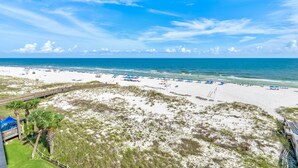 A beach with a wooden boardwalk, beach umbrellas, and palm trees. - Seaspray West 603- Gulf Front (Pensacola)