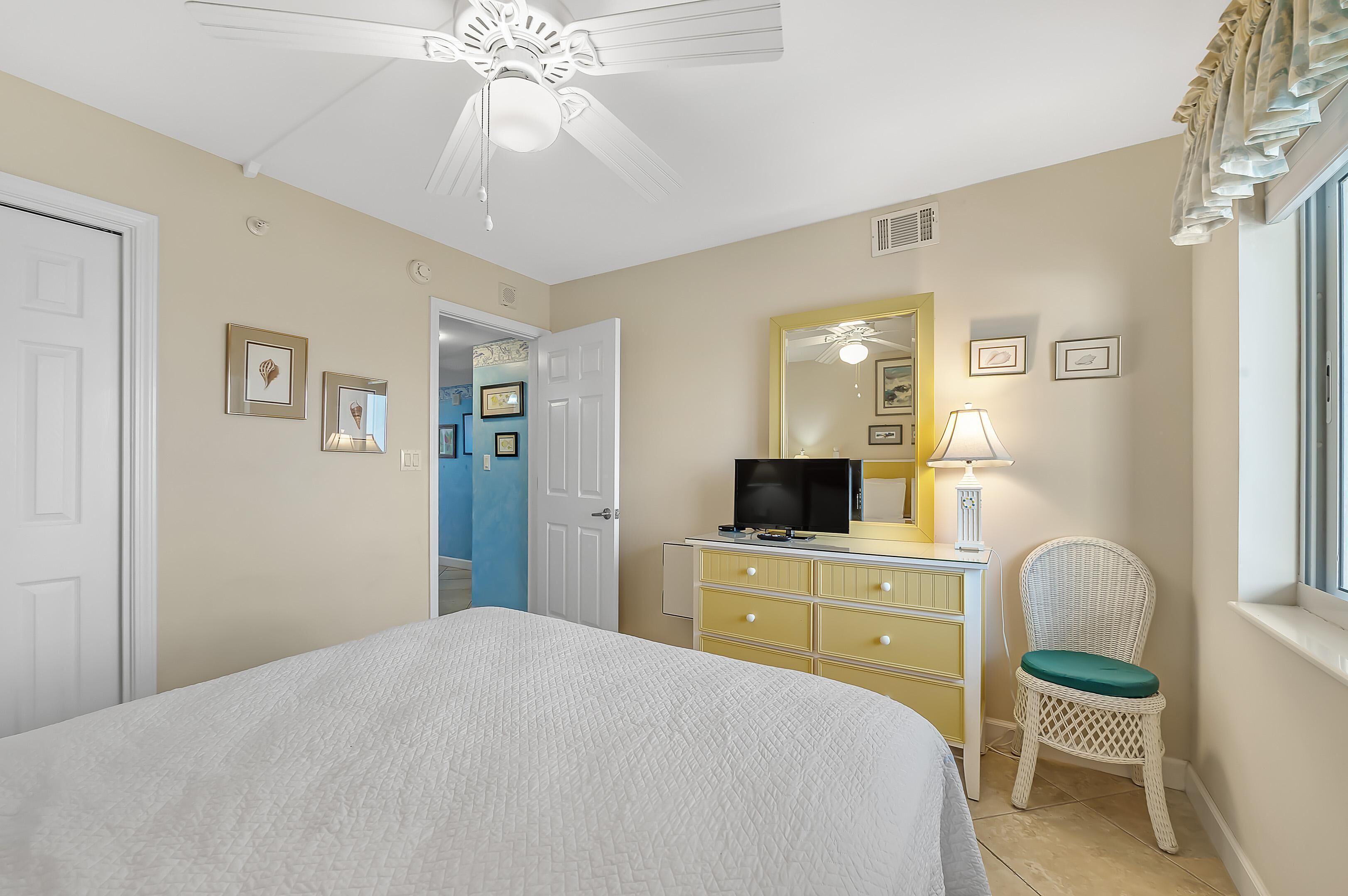 A bedroom with a bed, a dresser, a television, and a chair.