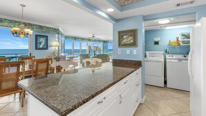 A kitchen with a granite countertop, white cabinets, and a view of the ocean. - Seaspray West 603- Gulf Front (Pensacola)