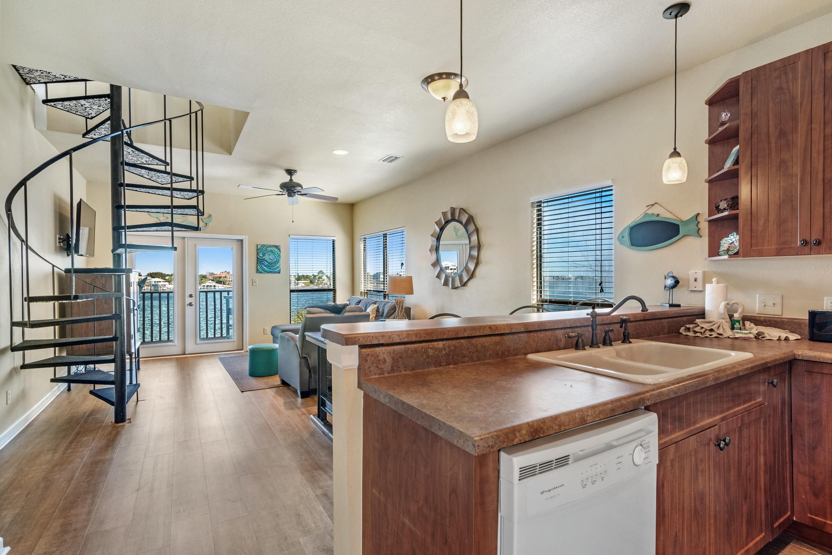 A modern kitchen with a central island, wooden cabinets, and a built-in dishwasher.