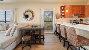 Une cuisine moderne avec des meubles en bois, un îlot central et un coin repas doté de chaises en osier.