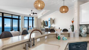 A modern kitchen with a large island, a built-in dishwasher, and a view of the ocean. - Phoenix West 2005 (Orange Beach)