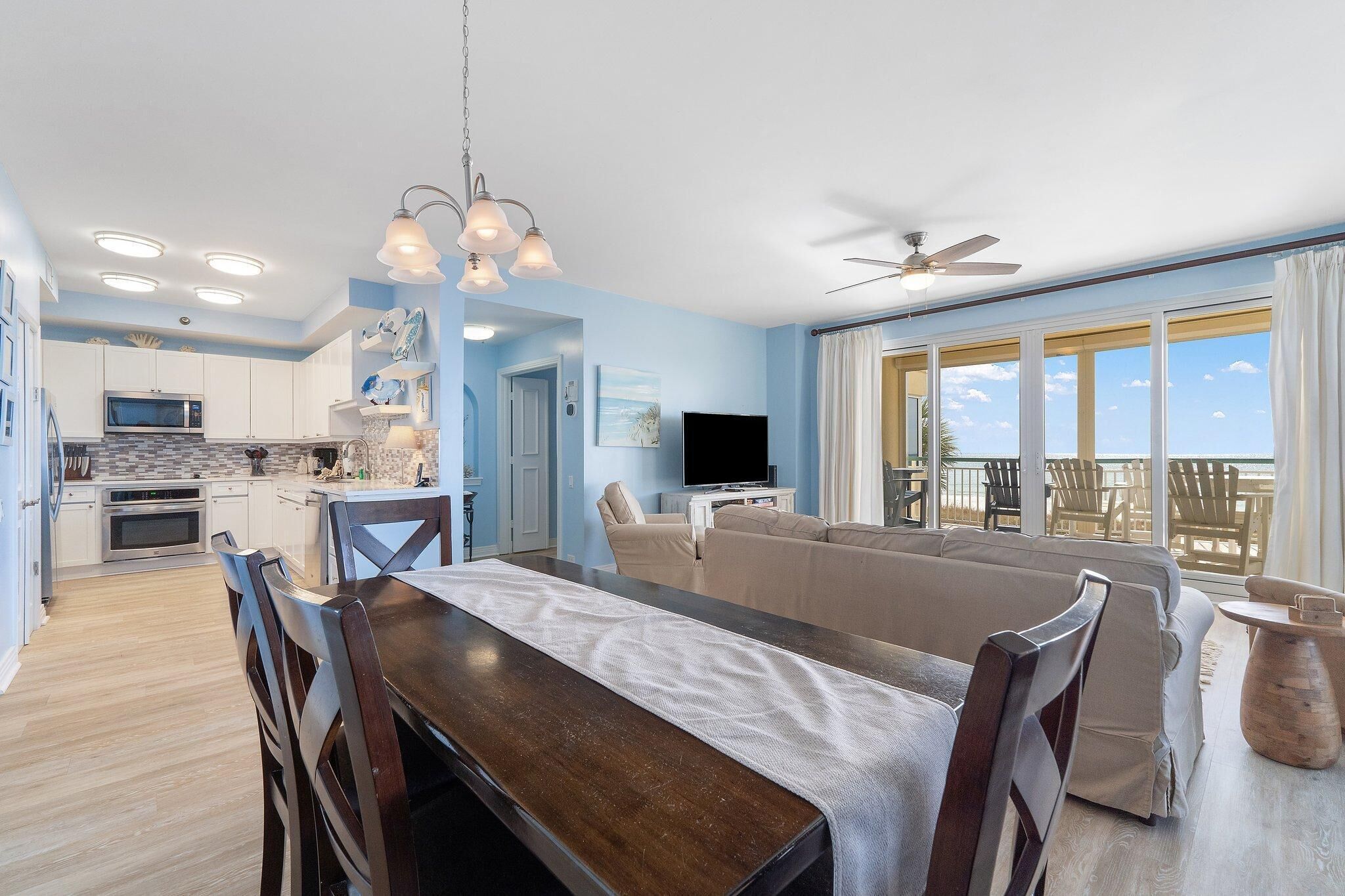 A modern living room with a dining area, a kitchen, and a large window overlooking the ocean.