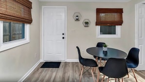 Un coin repas avec une table ronde, quatre chaises et un ventilateur de plafond.