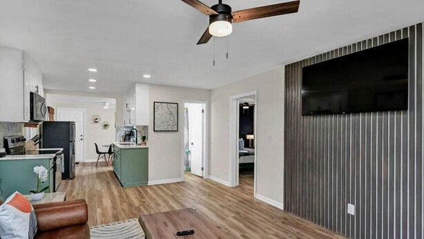 Un vaste espace de vie doté d’un plancher en bois, d’un canapé en cuir marron, d’une table basse en bois et d’un ventilateur de plafond.