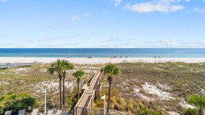 A beach view with a wooden boardwalk, palm trees, and a clear sky. - Capri 202 + Free Seasonal Beach Service (Pensacola)