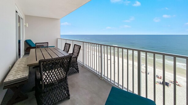 A balcony with a view of the beach, a table, chairs, and a bench. - Windemere 1003 (Pensacola)