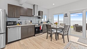 A modern kitchen with stainless steel appliances, dark wooden cabinets, and a view to the outside. - Whidbey Waterview Getaway: Nature, Deers, Pet & Family Friendly (Clinton)