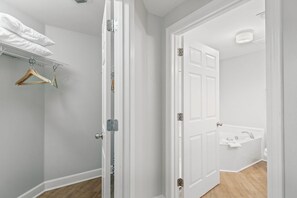 A room with a white door leading to a bathroom with a bathtub and sink. - Phoenix on the Bay 1228 (Orange Beach)