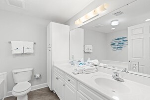 Un baño moderno con un lavabo blanco, dos espejos sobre el mueble y un inodoro.