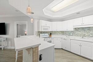 Una cocina moderna con armarios blancos, una isla central, un microondas y un salpicadero de azulejos.