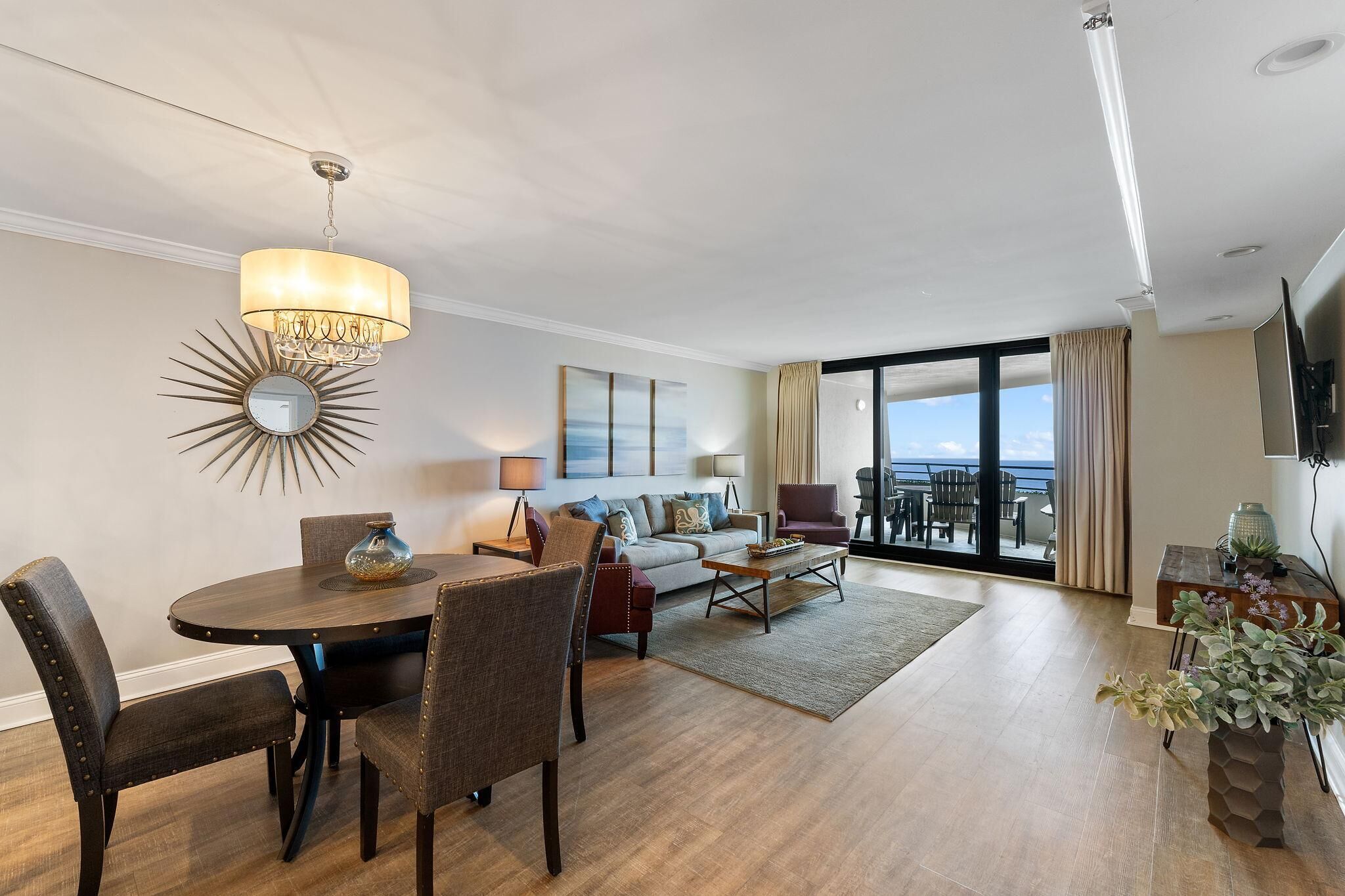A modern living room with a dining area, large windows, and a view of the ocean.