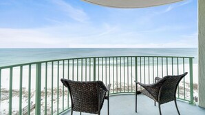 A balcony with two wicker chairs facing a beach. - Perdido Towers West 906 (Pensacola)