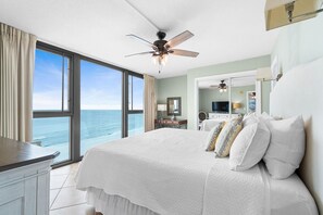 Een slaapkamer met een groot bed, een plafondventilator en uitzicht op de oceaan.