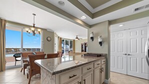 A kitchen with a large island, white cabinets, and a view to the outside. - Seaspray West 105- Gulf Front (Pensacola)