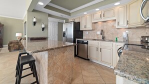 A modern kitchen with granite countertops, stainless steel appliances, and beige cabinetry. - Seaspray West 105- Gulf Front (Pensacola)