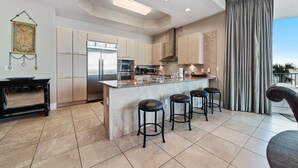 Een moderne keuken met een centraal eiland, barkrukken en een eethoek met een tafel.