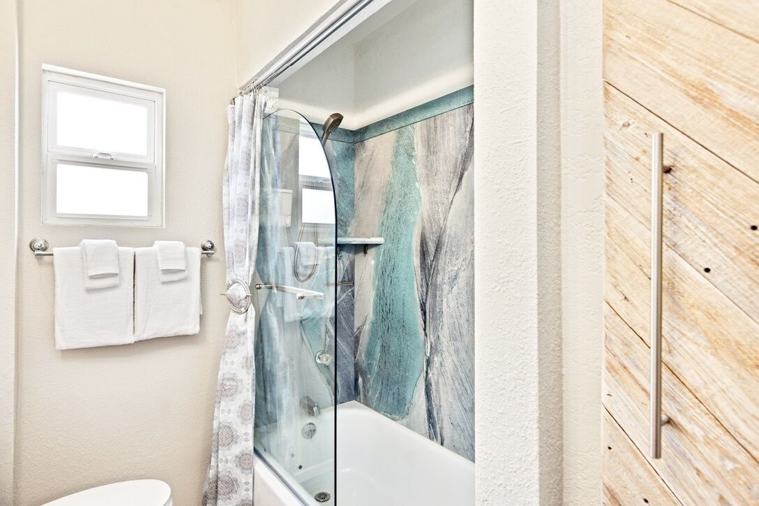 Ein Badezimmer mit einer gläsernen Duschkabine, einer weißen Badewanne und einer Holzpaneelausstattung.
