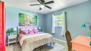 Une chambre à coucher avec un lit, un ventilateur de plafond, une fenêtre et un bureau.