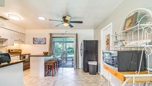Une cuisine dotée d’un îlot central, d’un ventilateur de plafond et donnant sur un patio.