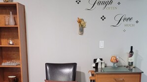 A dining area with a black leather chair, a wooden cabinet, and a wall with motivational decor. - Charming Cozy Suite In Langford. (Victoria)