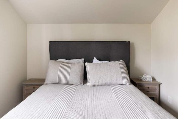 Un dormitorio con una cama, dos mesitas de noche y un cabecero.