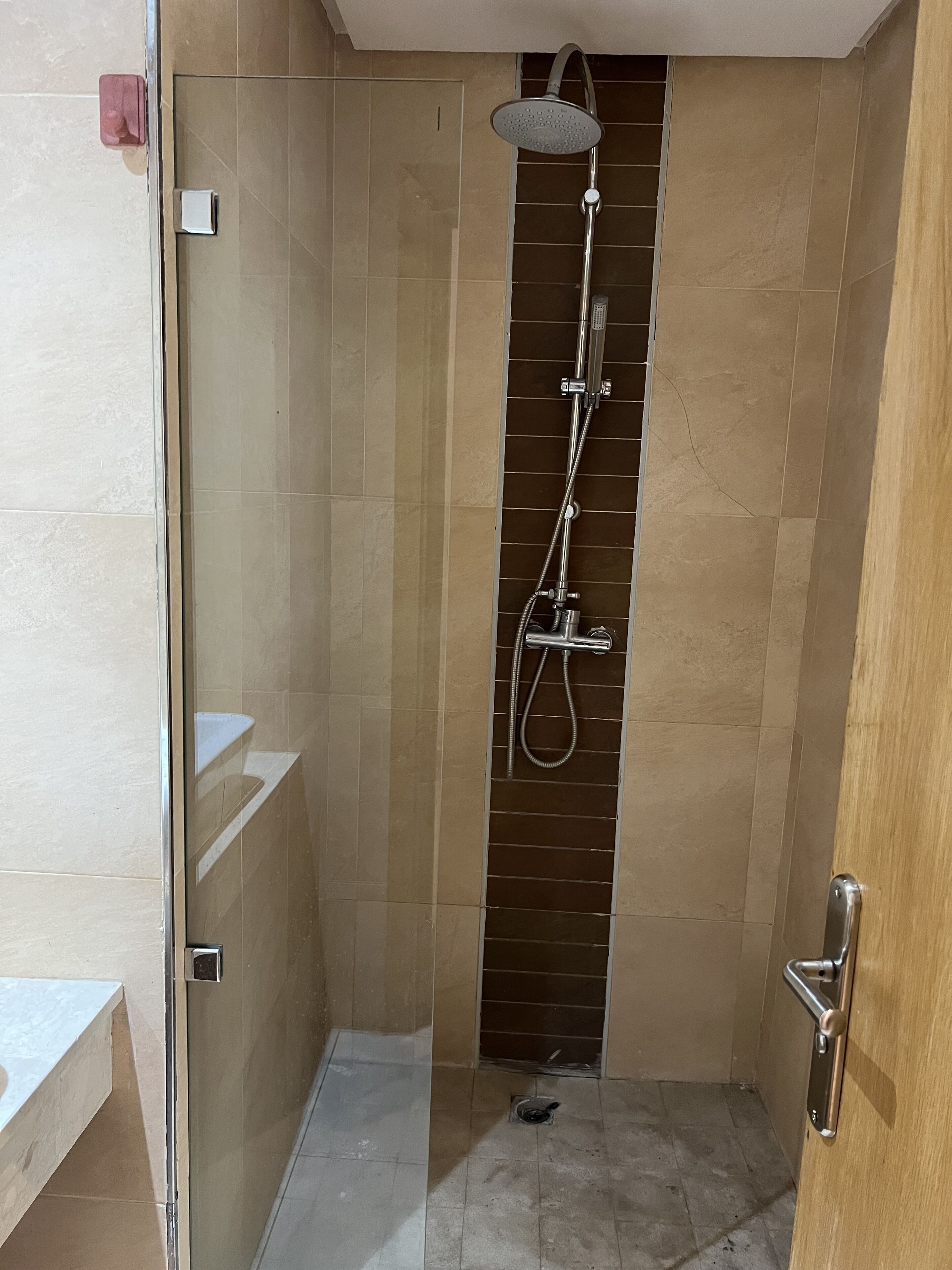 Ein modernes Badezimmer mit Dusche, gefliesten Wänden und einer Holztür.