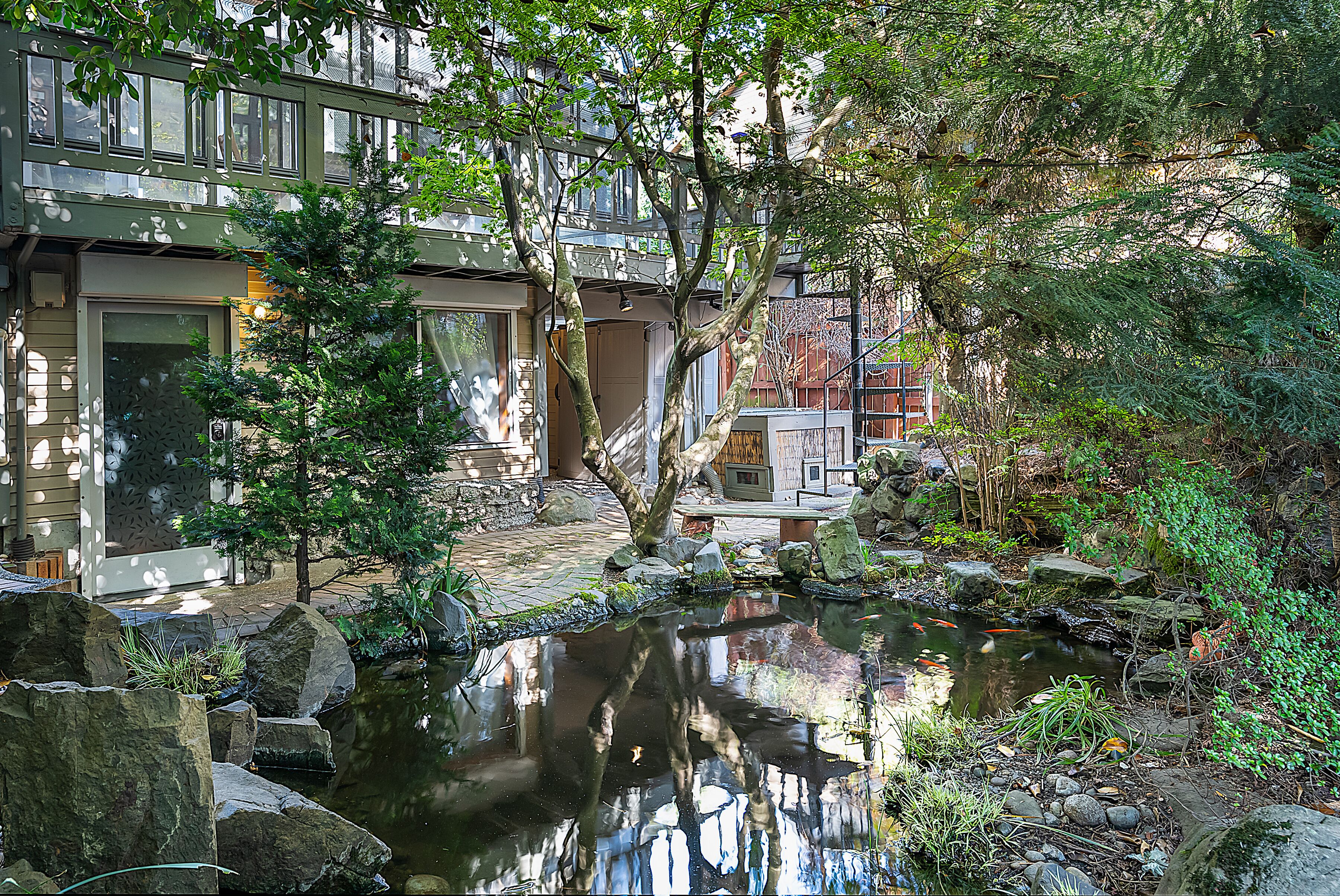 A serene garden with a pond, rocks, and a wooden bridge.