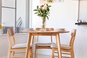 A dining area with a round wooden table, four chairs, and a vase with flowers.