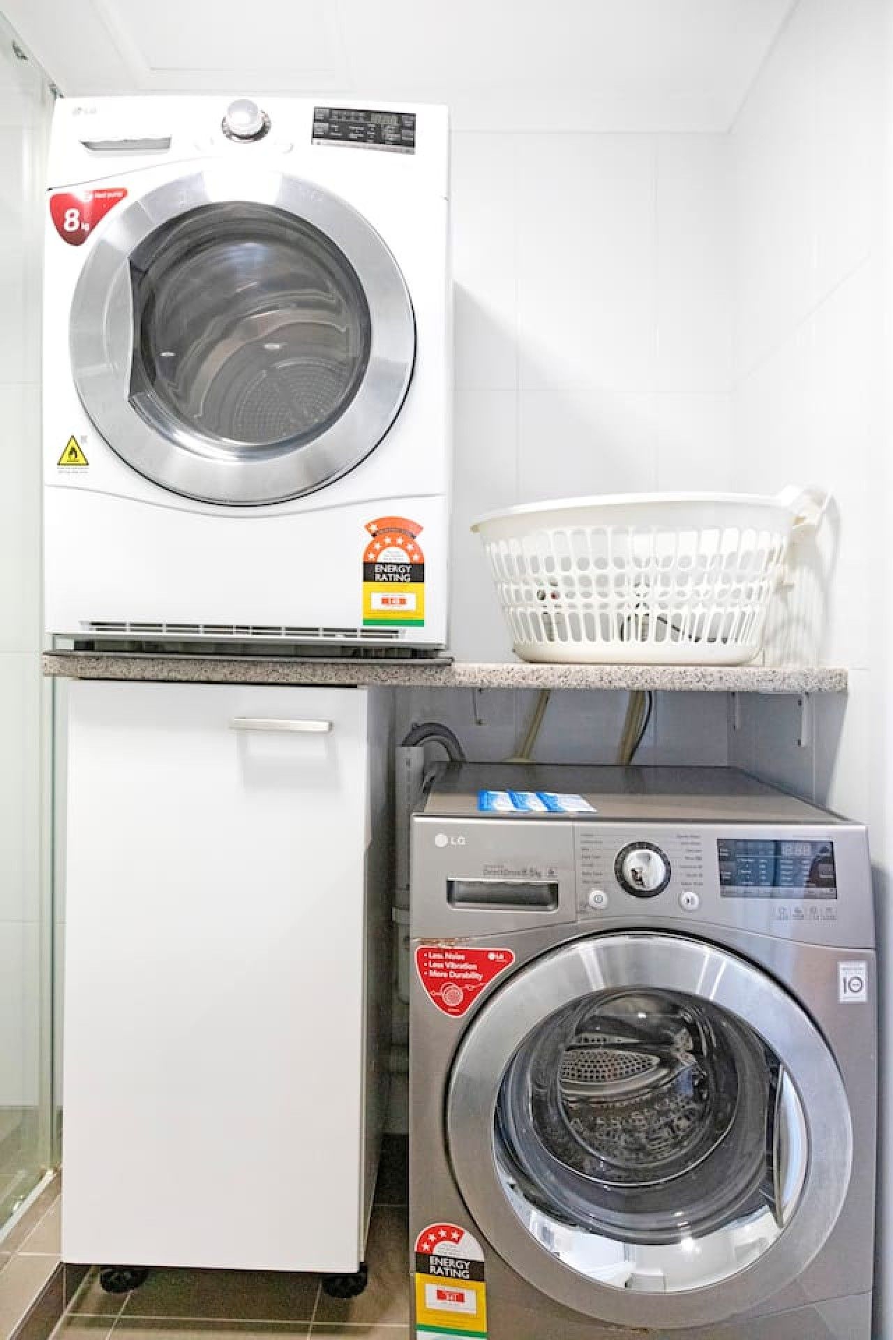 A laundry area with a front-loading washing machine and a stacked dryer.