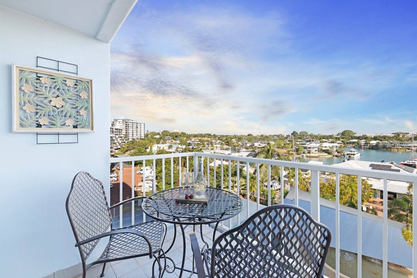 A balcony with a table and chairs, overlooking a marina and residential area.