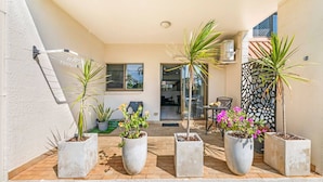 A covered patio area with potted plants and a seating area.