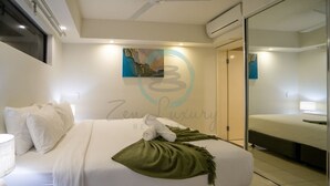 A modern hotel room with a large bed, a ceiling fan, and a glass door leading to a bathroom.
