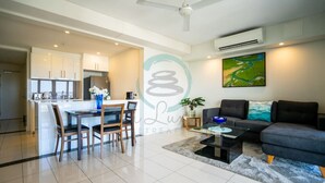 A modern living room with a sofa, coffee table, and a dining area with chairs and a table.