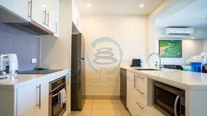 A modern kitchen with white cabinets, a built-in oven, a microwave, and a sink.