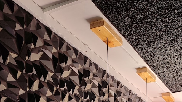 Angolo bar con parete a motivi geometrici, bancone in legno e sgabelli neri.