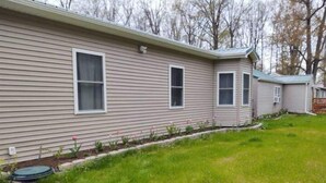 A single-story mobile home with a front yard and a small garden.