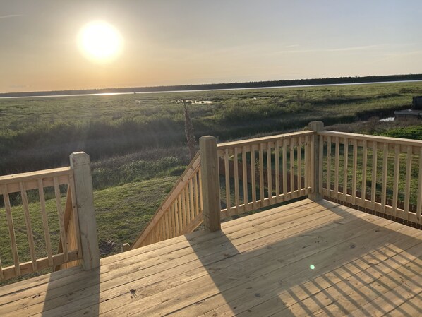 Una terraza de madera con vistas a un campo cubierto de hierba y una masa de agua.