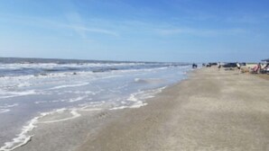 A beach with a sandy shore and ocean waves. - Beautiful NEW 2023 camper covered on concrete slab. Sit and enjoy the barges (Bolivar Peninsula)
