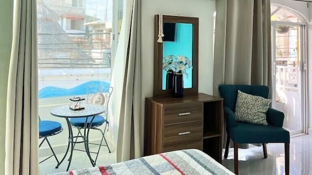 A hotel room with a bed, a desk with a chair, a small table with a chair, and a view of the outside.