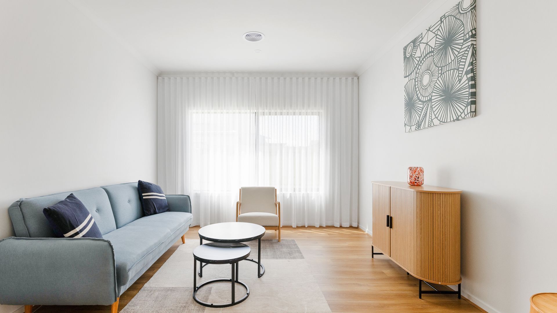 A modern living room with a sofa, a chair, a small table, and a cabinet.