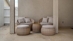 Un espace extérieur aménagé, abrité et doté de mobilier en osier et de coussins.
