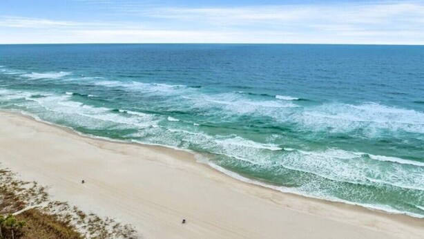 Une plage avec une eau d’un bleu limpide et un rivage sablonneux.