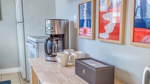 Eine Küchenzeile mit einer Kaffeemaschine, weißen Tassen und einer Schachtel auf der Arbeitsfläche.